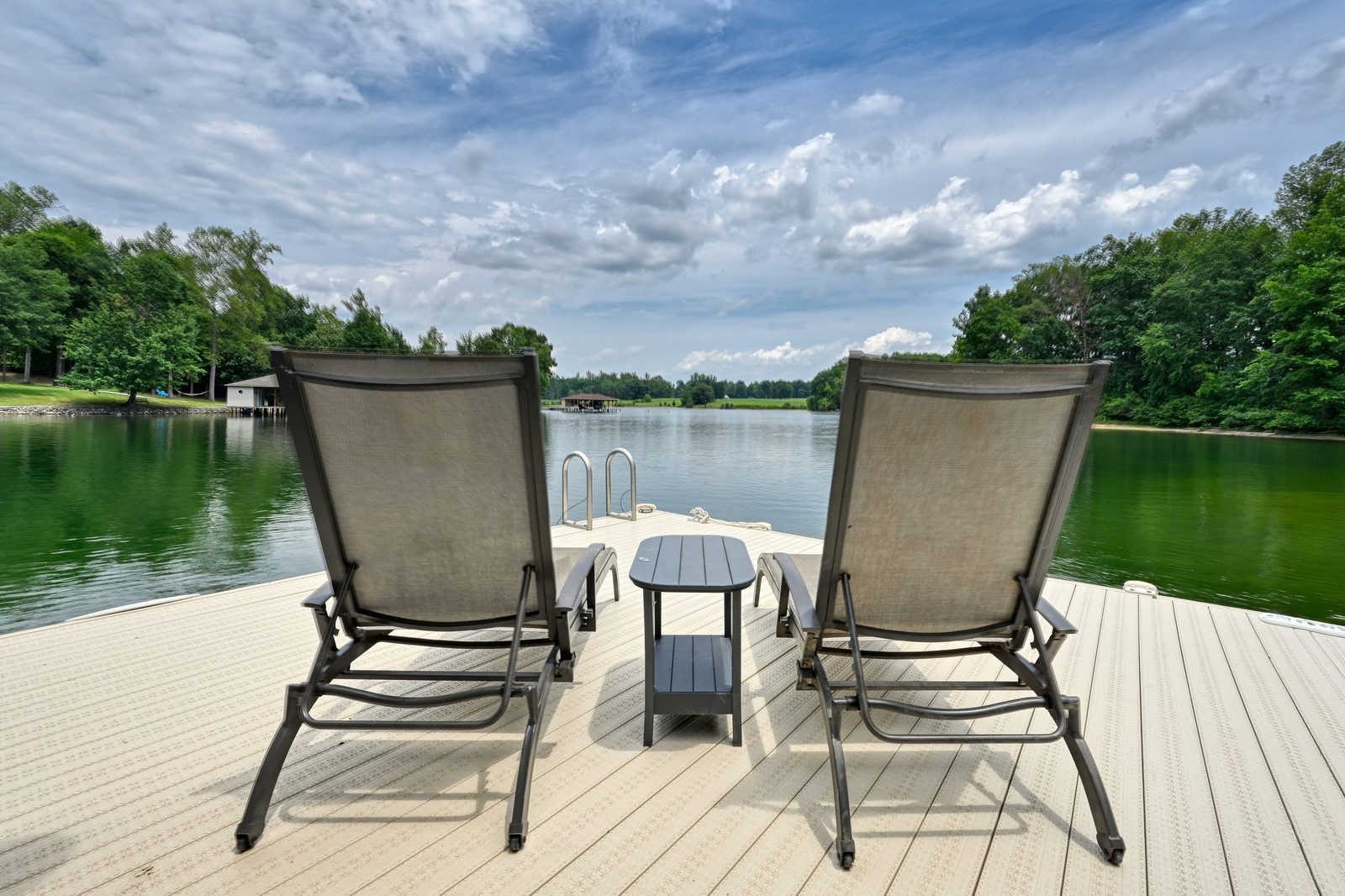 Two lounge chairs on the dock facing the lake